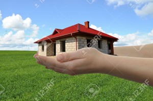11376508-House-in-hands-with-green-field-and-blue-sky-in-background-Stock-Photo